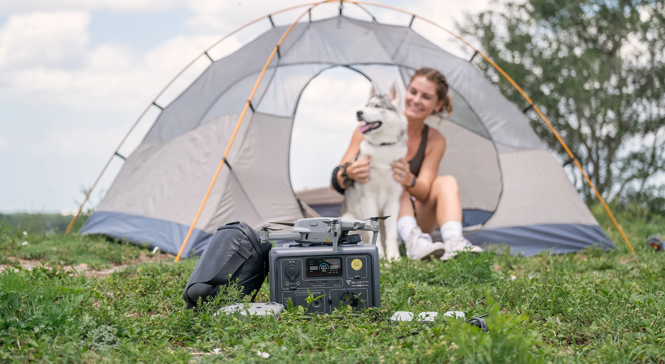 ragazza in campeggio con una batteria di accumulo portatile di fronte la tenda