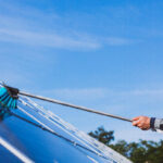 manutenzione dell'impianto fotovoltaico. Operaio che pulisce i pannelli solari con una spazzola telescopica