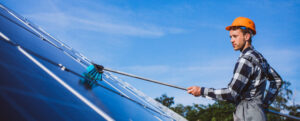 manutenzione dell'impianto fotovoltaico. Operaio che pulisce i pannelli solari con una spazzola telescopica